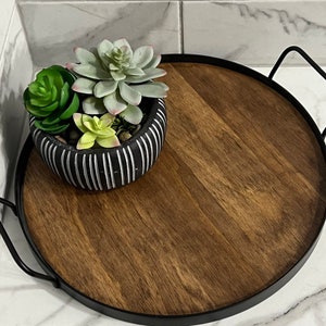 May include: A black metal tray with a wooden surface and a black and white striped planter with green succulents.