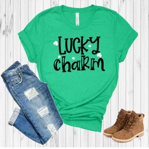 May include: A green t-shirt with the text "lucky charm" in black lettering and white shamrocks. The shirt is paired with blue jeans and brown boots.