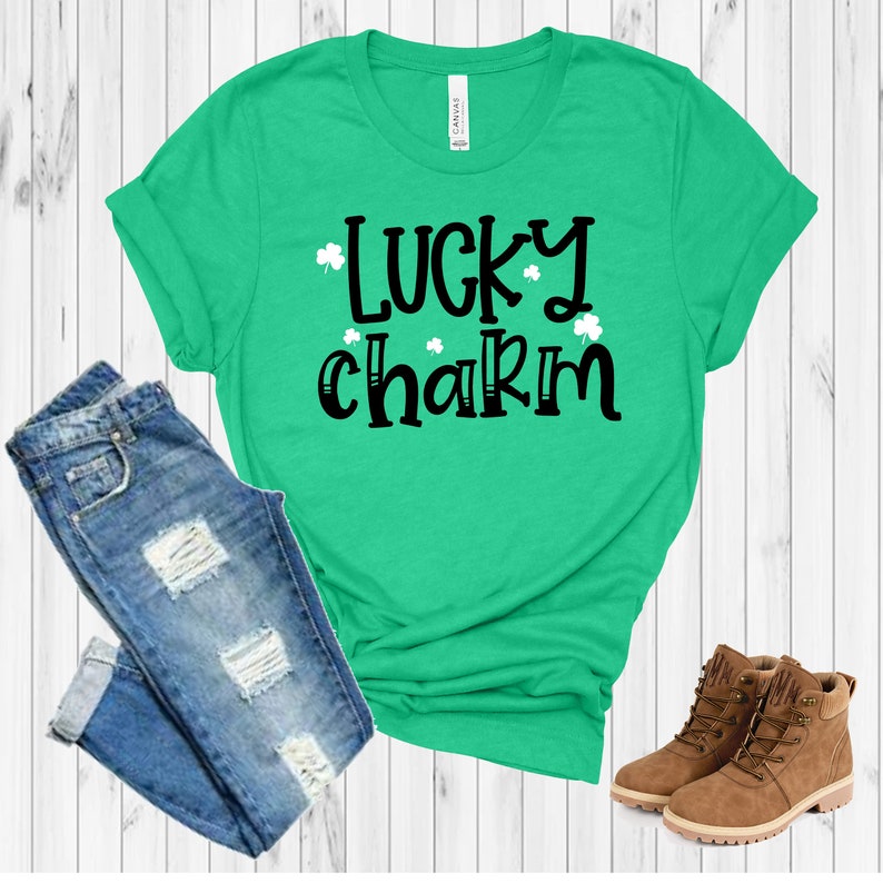 May include: A green t-shirt with the text "lucky charm" in black lettering and white shamrocks. The shirt is paired with blue jeans and brown boots.