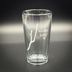 May include: A clear glass pint glass with an etched design of Keuka Lake, New York.
