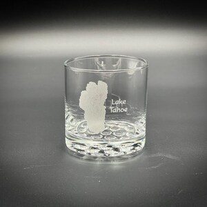 May include: A clear glass tumbler with a textured bottom. The glass has an etched design of Lake Tahoe and its outline.