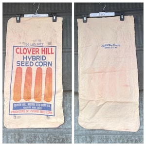 May include: Vintage Clover Hill Hybrid Seed Corn bag. The front of the bag features the text "CLOVER HILL HYBRID SEED CORN" with illustrations of four ears of corn. The bag is labeled "56 LBS. NET". The back of the bag has the text "Central Bag Company, Kansas City, MO."