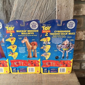 May include: Toy Story 2 action figures, including Bullseye and Techno Gear Buzz, in their original packaging. The packaging is blue and yellow with the Disney Pixar logo and Silver Edition labels. The Bullseye figure is brown and the Buzz figure is silver.