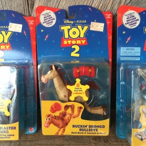 May include: Three vintage Toy Story 2 action figures in their original packaging. The packaging is blue and red with the Disney Pixar logo. One figure is Buckin' Bronco Bullseye, a brown horse with a red saddle. The packaging reads "Silver Edition Collector Items!"