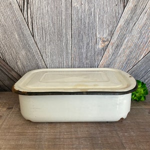 May include: White enamelware baking dish with a black rim and lid. The dish is rectangular and has a slightly rounded shape.