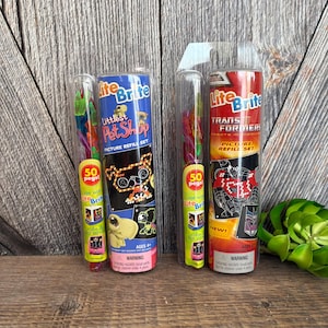 May include: Two Lite-Brite picture refill sets. One is Littlest Pet Shop themed, the other is Transformers themed. Each set includes 50 pegs and a picture refill set. The packaging is cylindrical with clear plastic fronts.