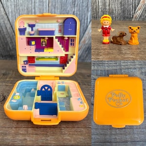 May include: An open, orange Polly Pocket compact toy with a miniature house interior, including a bathroom, kitchen, and stairs. Includes a doll, a brown dog, and an orange cat figurine. The closed compact has the words "Polly Pocket" on the front.