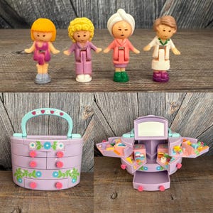 May include: A collection of vintage miniature doll figures and a matching dollhouse playset. The figures include four dolls with different hairstyles and outfits. The dollhouse is lavender with a handle and flower details, and opens to reveal multiple compartments.