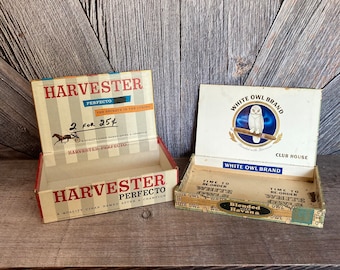 May include: Two vintage cigar boxes. The first box is red, white, and blue with the text "Harvester Perfecto" and "2 for 25¢". The second box is white with the text "White Owl Brand" and a white owl illustration.