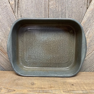 May include: A gray enamel baking dish with a speckled pattern. The dish is rectangular with rounded corners and has a slight lip around the edge.