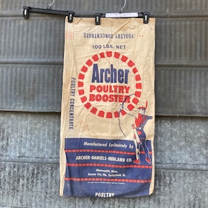 May include: A vintage Archer Poultry Booster feed bag, featuring a red, white, and blue design with a cartoon archer. The bag is made of brown paper and has the text "POULTRY CONCENTRATE" printed on the side. The bag is labeled "100 LBS. NET" and "44".