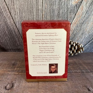 May include: Red box with a white border and a picture of Santa Claus on the front. The back of the box has text that reads "Features clip-on attachment for optional decorative lighting effect." and "This charming depiction of Santa's departure illustrates the closing verse of Clement Clarke Moore's The Night Before Christmas: But I heard him exclaim, ere he drove out of sight, "Happy Christmas to all, and to all a good night!" This ornament is one of four Keepsake of Membership ornaments commemorating the 175th year of The Night Before Christmas, which was written in 1822. Sculpted by Nello Williams For decorative use only Not for young children Memories Traditions Handcrafted - Dated 1997"