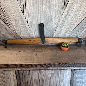 May include: A rustic wooden yoke with metal hardware and a black metal bracket. The yoke is a light brown color and has a small terracotta pot with a succulent plant on a wooden shelf.