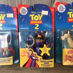 May include: Three vintage Toy Story 2 action figures in their original packaging. The figures include Zurg, a prospector, and a horse. The packaging features the Disney Pixar logo and the text "Silver Edition Collector Items!"