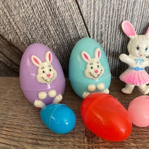 May include: A set of six plastic Easter eggs with bunny faces. The eggs are in various colors, including purple, blue, red, and pink.
