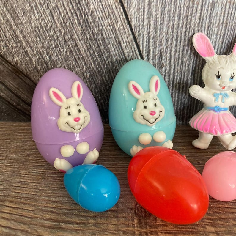 May include: A set of six plastic Easter eggs with bunny faces. The eggs are in various colors, including purple, blue, red, and pink.