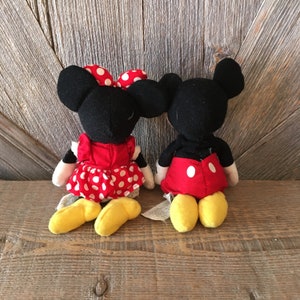 K&ouml;nnte beinhalten: Ein Paar Pl&uuml;schtiere von Mickey Mouse und Minnie Mouse. Mickey tr&auml;gt eine rote Hose mit wei&szlig;en Punkten und Minnie tr&auml;gt ein rotes Kleid mit wei&szlig;en Punkten. Beide Spielzeuge haben schwarze Ohren und gelbe Schuhe.
