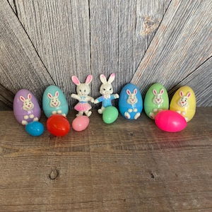May include: Eight plastic Easter eggs, some with bunny faces, in various colors, including purple, blue, green, yellow, and pink. Two bunny figurines are also included, one in pink and one in blue.