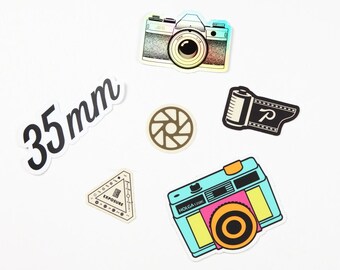 May include: A set of five colorful stickers featuring a camera, film roll, aperture, and the text "35mm" and "HOLGA 120K".