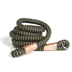 May include: A green and black braided camera strap with a brown leather accent. The strap is coiled and ready to be attached to a camera.
