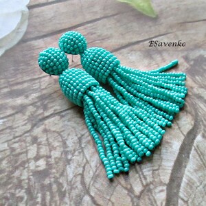 May include: A pair of turquoise beaded tassel earrings. The earrings are made of small, round beads that are strung together to create a tassel effect. The earrings are approximately 7.5 cm long.