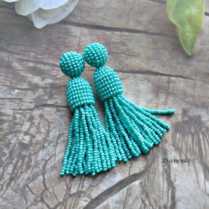 May include: A pair of turquoise beaded tassel earrings. The earrings are made of small, round beads that are strung together to create a tassel shape. The tassels are approximately 5 cm long.