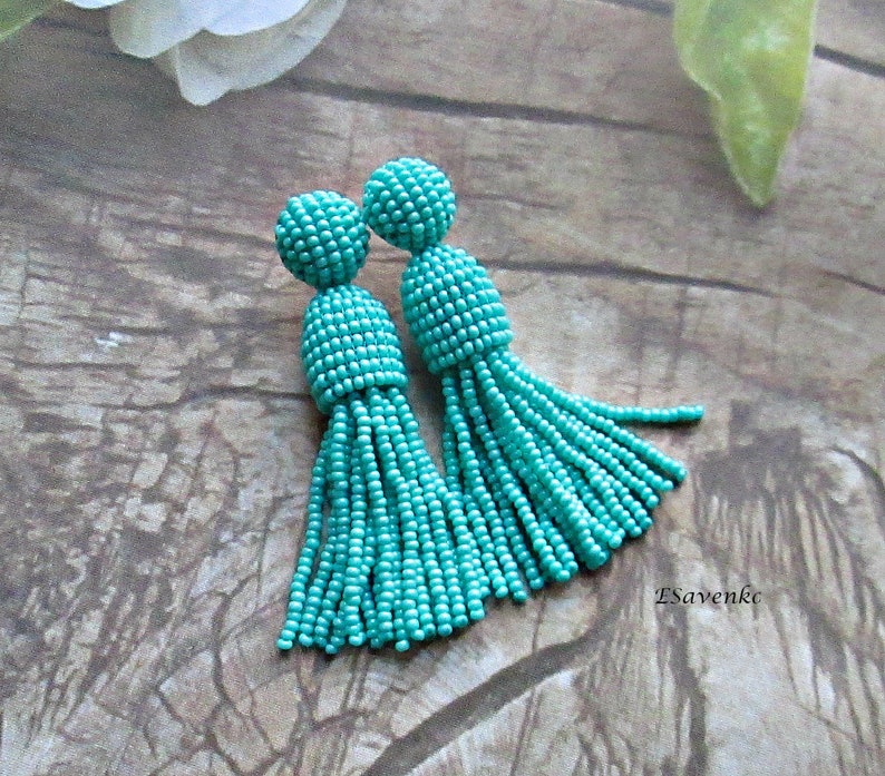 May include: A pair of turquoise beaded tassel earrings. The earrings are made of small, round beads that are strung together to create a tassel shape. The tassels are approximately 5 cm long.