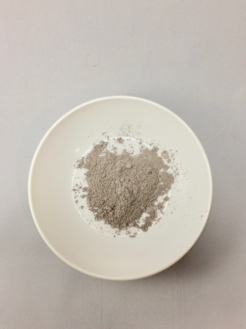 May include: A white ceramic bowl filled with a pile of gray powder.