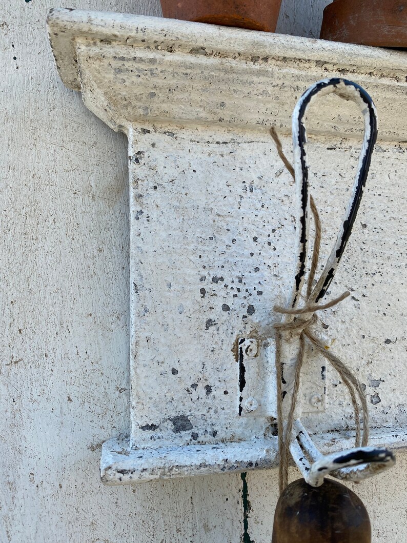 Peut inclure: &Eacute;tag&egrave;re en m&eacute;tal peinte en blanc avec un seul crochet en m&eacute;tal noir et blanc. Le crochet est entour&eacute; d'une ficelle brune.