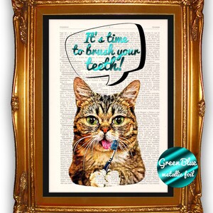 May include: Framed art print featuring a tabby cat holding a toothbrush. The cat is depicted on a vintage book page background. A speech bubble above the cat reads "It's time to brush your teeth!" in teal lettering. The frame is gold.