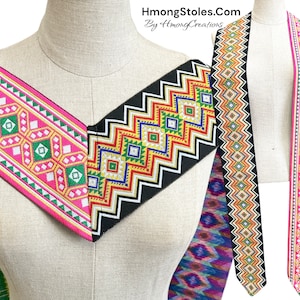 May include: Two Hmong fabric trim stoles with geometric patterns in pink, green, yellow, and black. The stoles are displayed on a mannequin and are available for purchase at HmongStoles.com.