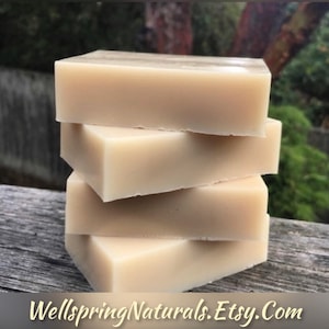 Può includere: Quattro saponette naturali impilate l'una sull'altra. Il sapone è di colore beige chiaro. Il sapone è su una superficie di legno. Il testo "Wellspring Naturals. Etsy.com" è visibile nella parte inferiore dell'immagine.