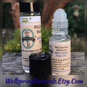 May include: Two clear glass roller bottles with black caps and white labels. The labels feature the text Wellspring Naturals ZZZ's Please Sleep Oil, instructions to apply to wrists and back of the neck, and a list of ingredients including coconut oil.