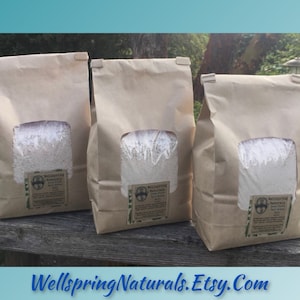 May include: Three brown paper bags filled with white powder. Each bag has a label that says "Wellspring Naturals Bath Soak".
