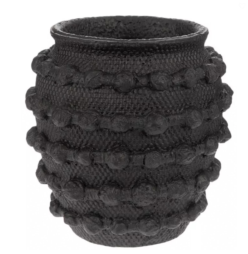K&ouml;nnte beinhalten: Eine schwarze dekorative Vase mit strukturierter Oberfl&auml;che und einer Reihe erhabener, abgerundeter Verzierungen. Die Vase hat eine breite, offene Oberseite und eine leicht bauchige Form, geeignet f&uuml;r die Inneneinrichtung.
