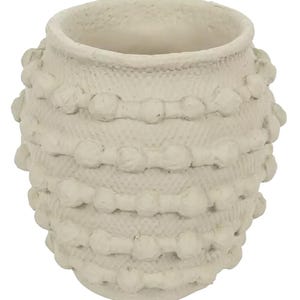 K&ouml;nnte beinhalten: Cremefarbene Keramikvase mit strukturierter Oberfl&auml;che und runder Form. Die Vase hat ein gewebtes Muster mit kugelf&ouml;rmigen Verzierungen. Die offene Oberseite und die strukturierte Oberfl&auml;che verleihen ihr ein rustikales, handwerkliches Aussehen. Ideal f&uuml;r die Inneneinrichtung.