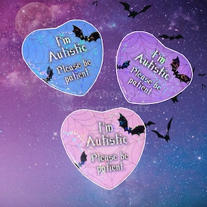 May include: Three heart-shaped stickers with the text "I'm Autistic Please be patient." The stickers are blue, purple, and pink, with a spiderweb design and bat illustrations. The background is a starry night scene with bats.