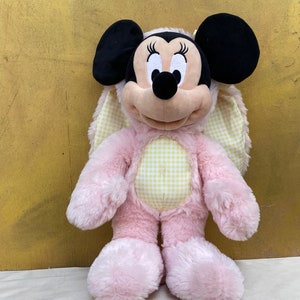 May include: Pink plush Easter bunny with yellow and white gingham fabric on the chest and ears. The bunny has black ears and a black nose. The bunny is a Mickey Mouse character.