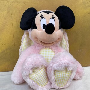 May include: Pink plush Minnie Mouse wearing a yellow and white gingham bunny costume.