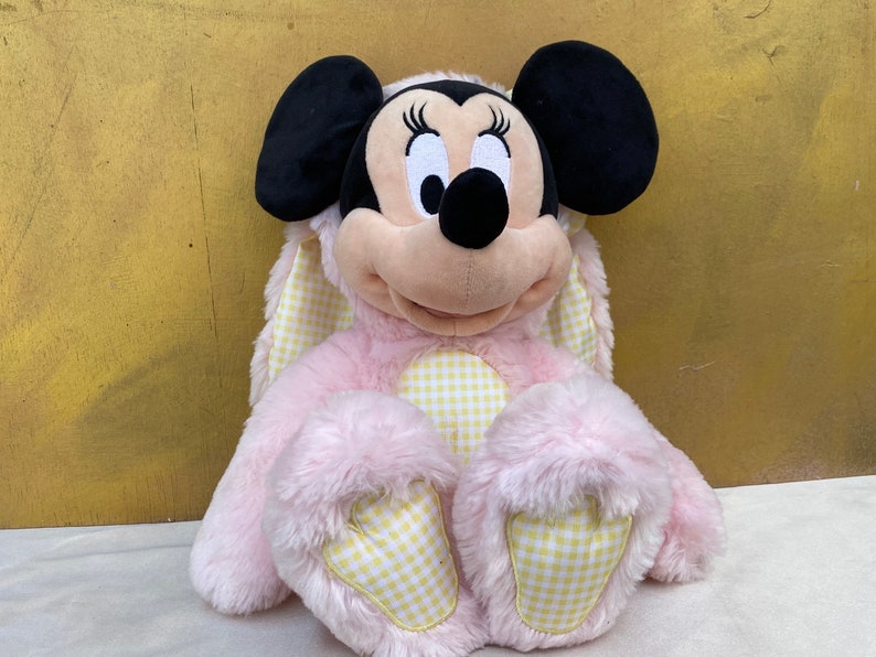 May include: Pink plush Minnie Mouse wearing a yellow and white gingham bunny costume.