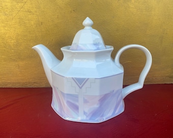 May include: White teapot with a lavender and gray geometric design. The teapot has a lid and a handle.