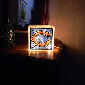 Peut inclure: Une lampe en verre teint&eacute; avec un logo "C" de Chicago bleu et orange. La lampe est allum&eacute;e et diffuse une lueur chaude.