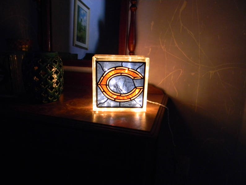 Peut inclure: Une lampe en verre teint&eacute; avec un logo "C" de Chicago bleu et orange. La lampe est allum&eacute;e et diffuse une lueur chaude.
