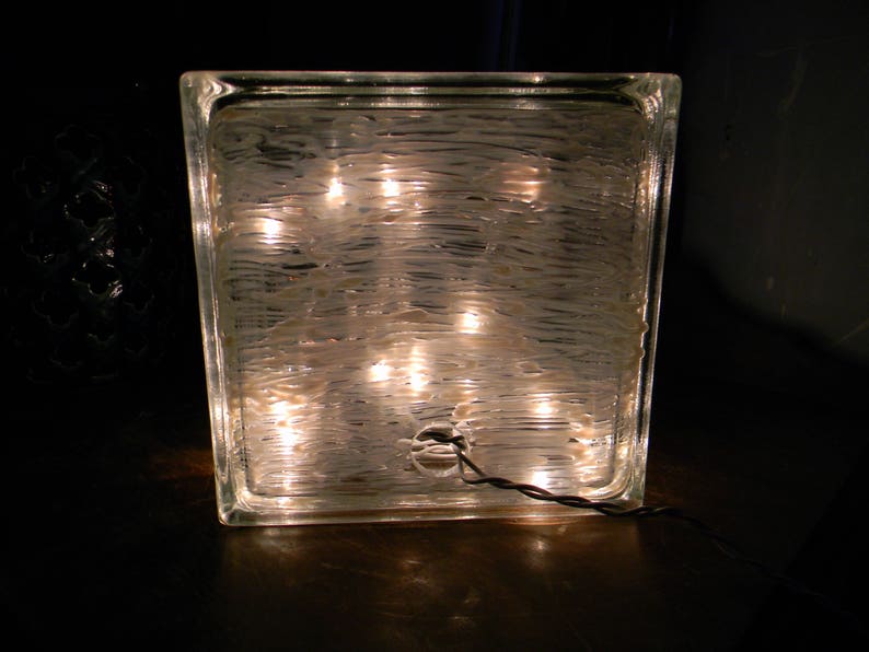 Peut inclure: Un bloc de verre transparent avec une surface textur&eacute;e et plusieurs petites lumi&egrave;res &agrave; l'int&eacute;rieur. Les lumi&egrave;res illuminent le bloc de verre de l'int&eacute;rieur, cr&eacute;ant une lueur chaleureuse.