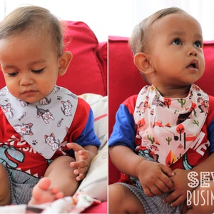 May include: Two babies wearing colorful bibs with different patterns. The bib on the left has a gray background with white cats and fish. The bib on the right has a white background with a colorful pattern of trees, mountains, and cacti. The text "SEW BUSINESS" is visible in the bottom right corner of the image.