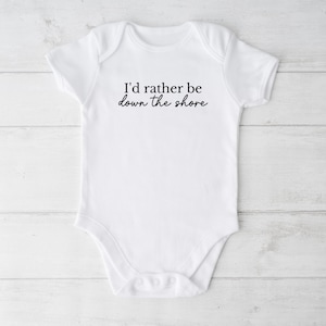 May include: White baby onesie with short sleeves and a black text graphic that reads "I'd rather be down the shore".