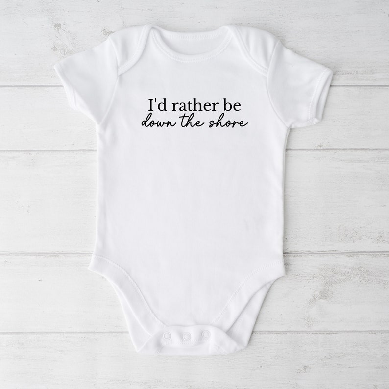 May include: White baby onesie with short sleeves and a black text graphic that reads "I'd rather be down the shore".
