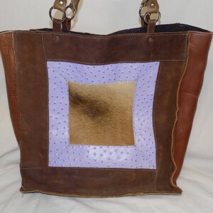 Op de afbeelding: Een bruine leren tote bag met een paars en bruin patroon. De tas heeft een groot vierkant stuk bruin bont in het midden.