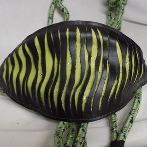 Puede incluir: Un collar de cuero negro con estampado de cebra verde y pedrería. El collar está unido a una cuerda verde.