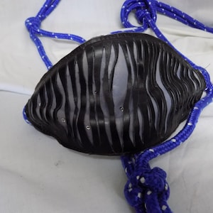 Puede incluir: Un bozal de cuero negro para caballo con una cuerda azul atada. El bozal tiene un diseño único con recortes y pedrería.